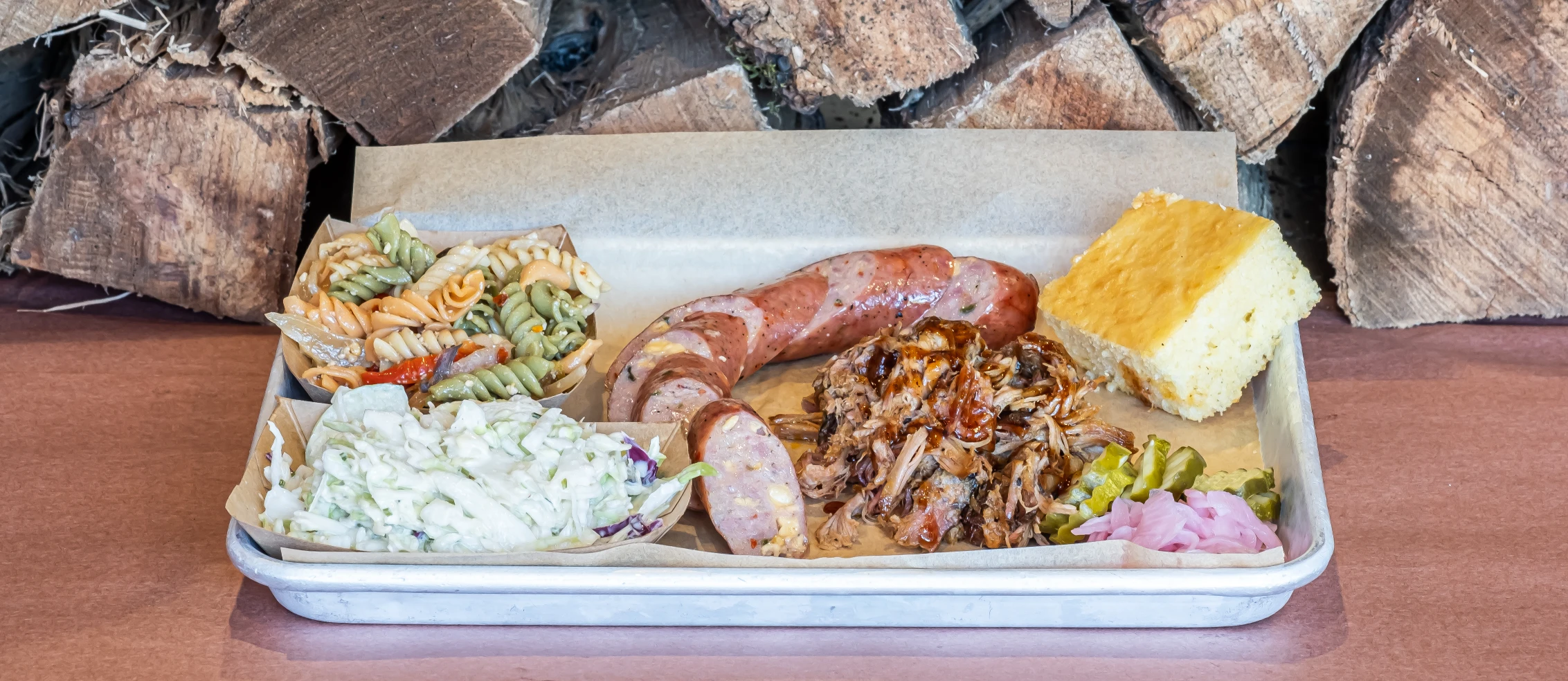 porky-butts-bbq-menu-1 jalapeno cheddar sausage and sides at porky butts bbq against a wood background