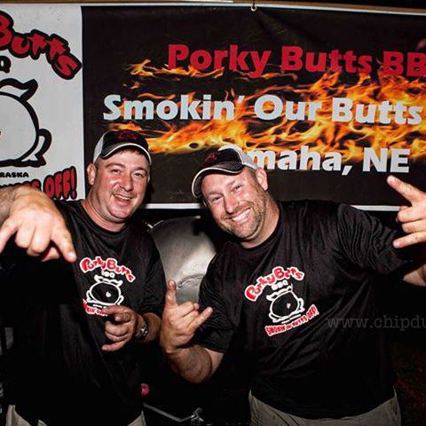blane and another man posing in front of the porky butts bbq sign
