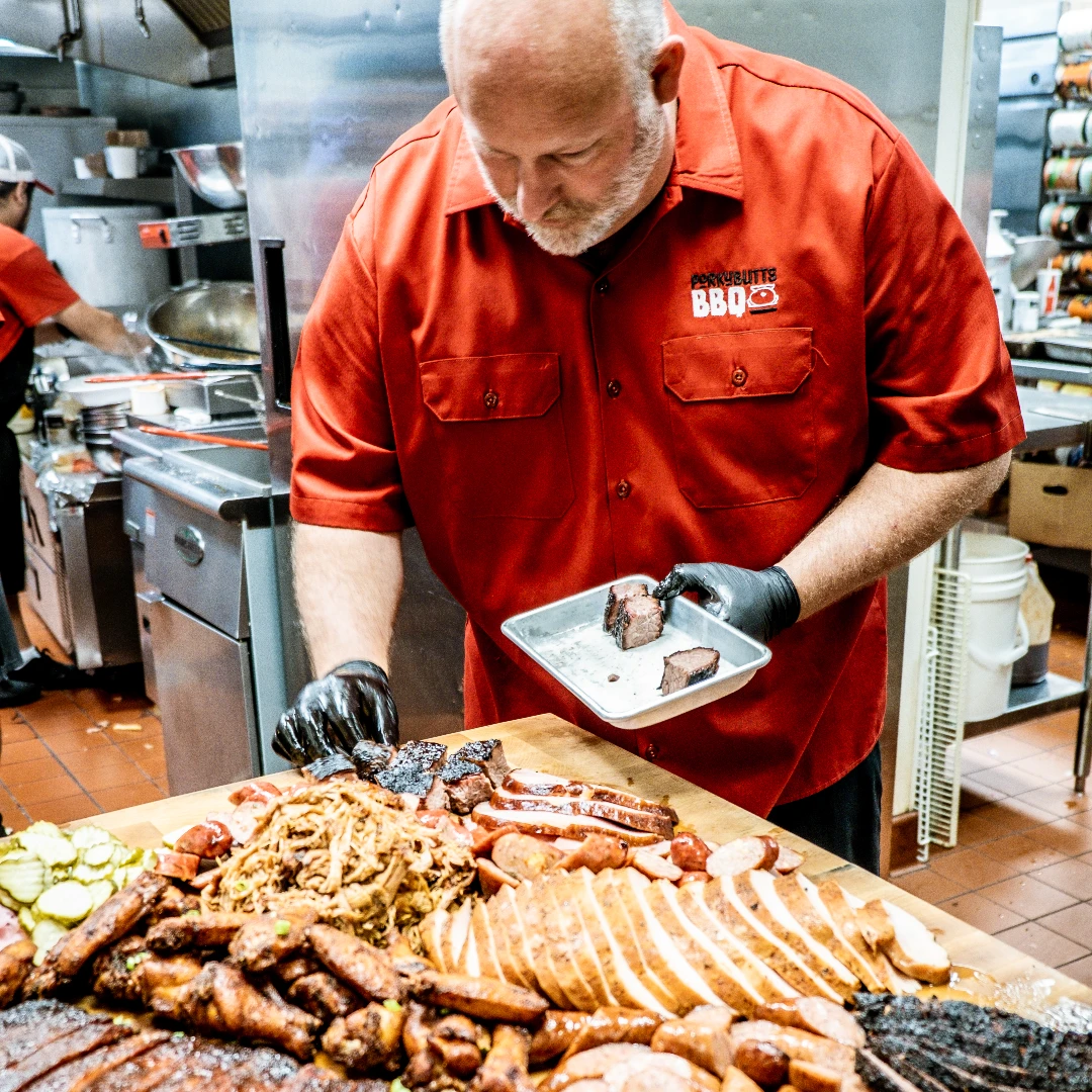blane hunter of porky butts bbq finishing a tray of meat